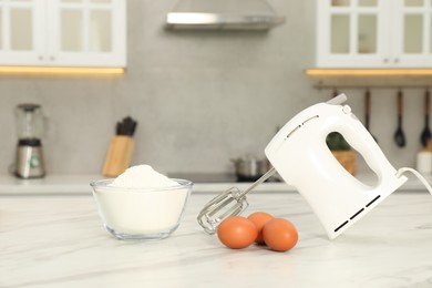 Photo of Modern mixer, eggs and bowl with flour on white marble table in kitchen