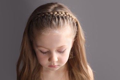 Photo of Little girl with braided hair on grey background. Space for text