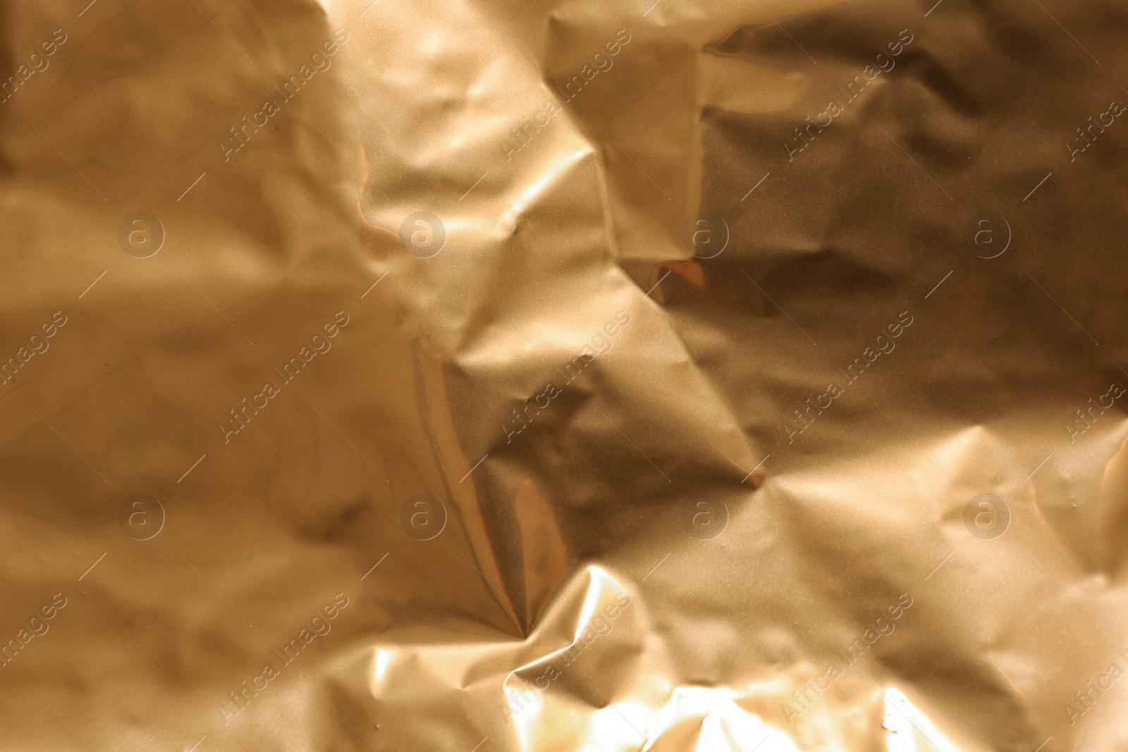 Photo of Crumpled golden paper as background, closeup view