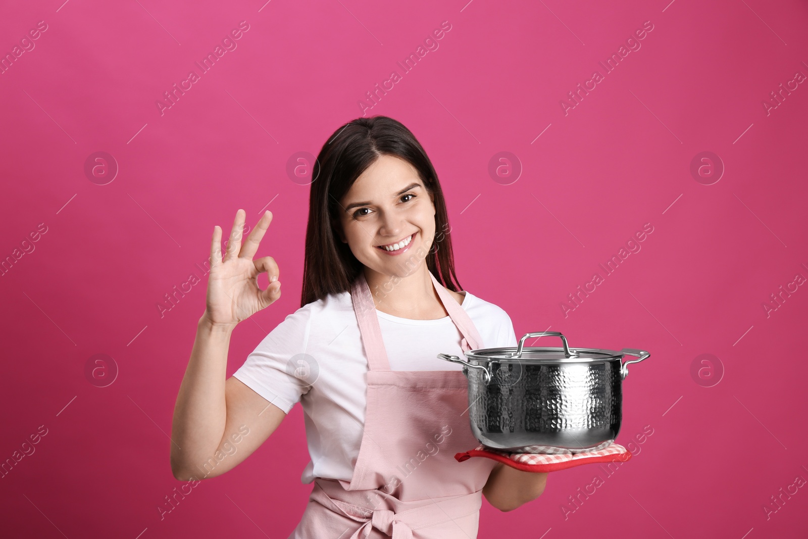 Photo of Happy young woman with cooking pot on pink background