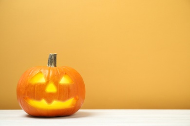 Photo of Scary jack o'lantern pumpkin on yellow background, space for text. Halloween decor