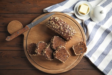 Photo of Tasty rye bread served on wooden table, flat lay