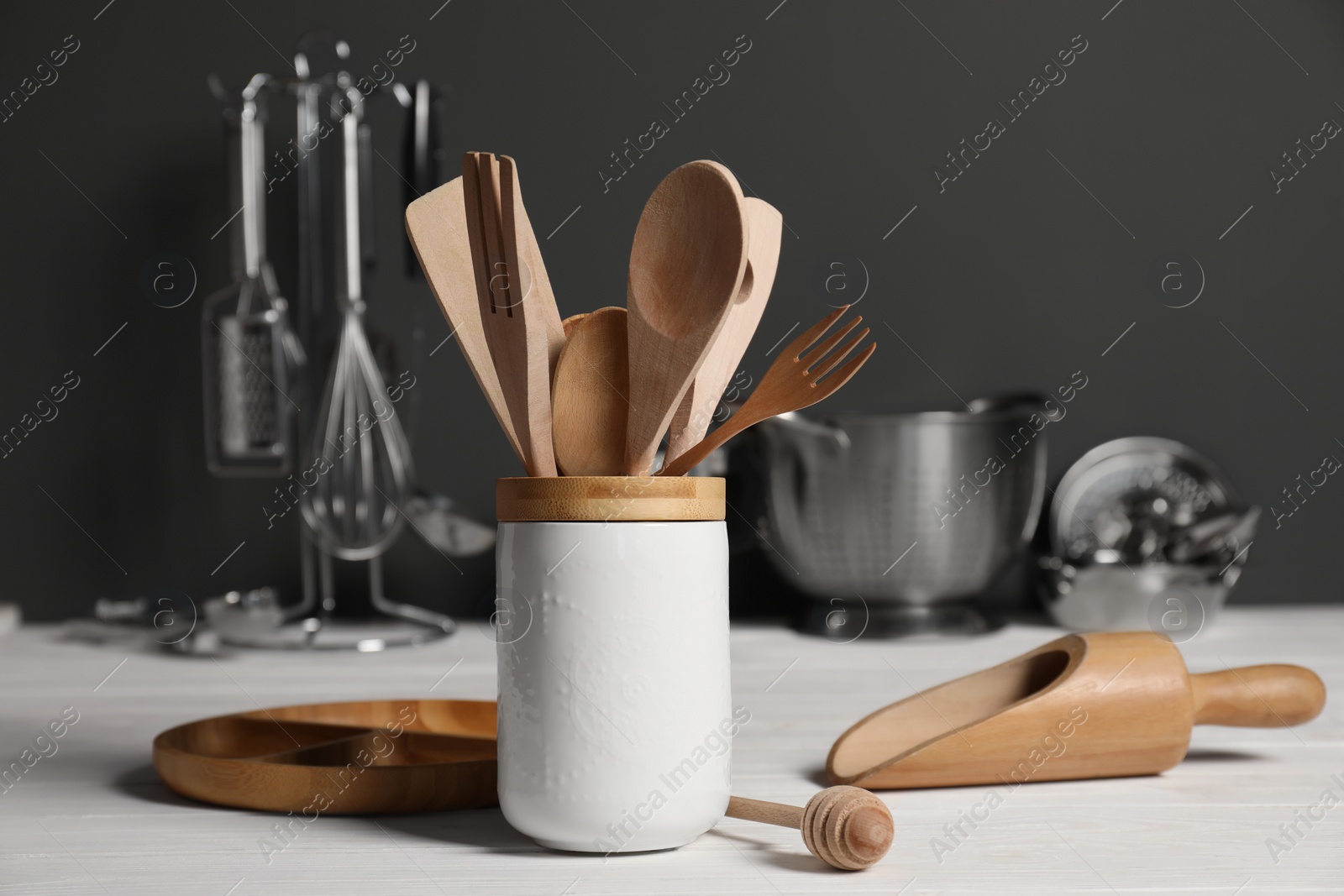 Photo of Set of different kitchen utensils on white wooden table against grey background