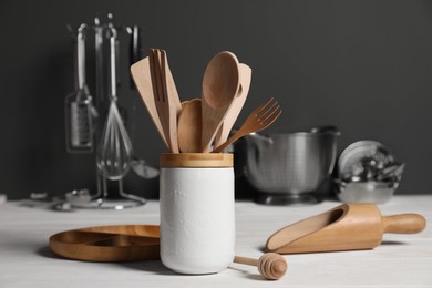 Set of different kitchen utensils on white wooden table against grey background