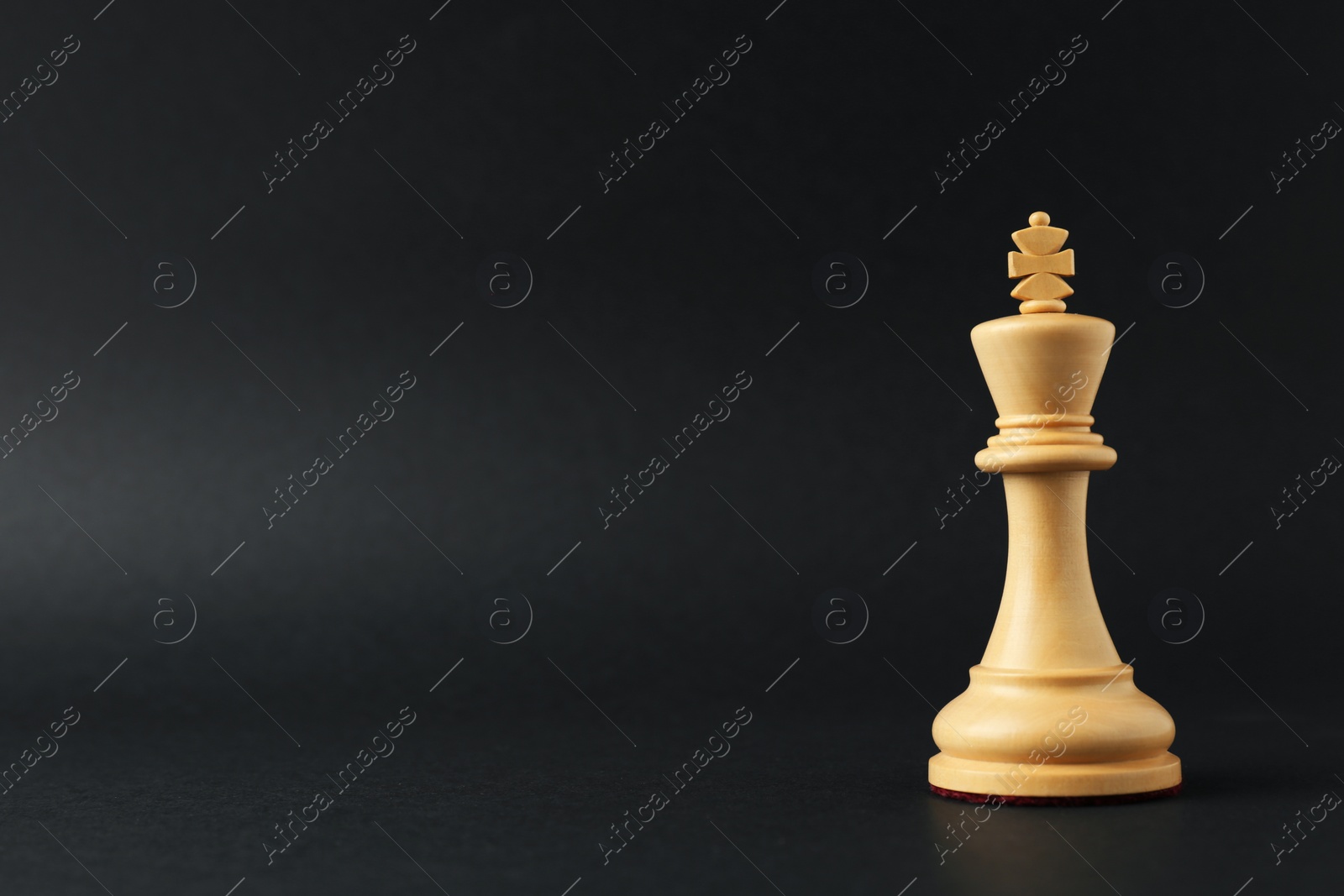 Photo of Wooden king on dark background, space for text. Chess piece
