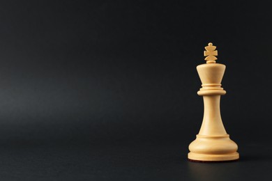 Wooden king on dark background, space for text. Chess piece