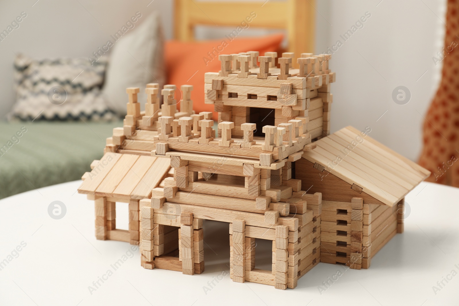 Photo of Wooden castle on white table indoors. Children's toy