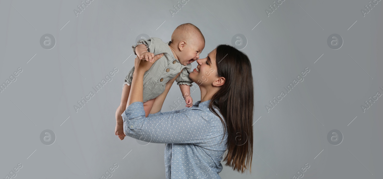 Image of Beautiful mother with her cute baby on grey background. Banner design 