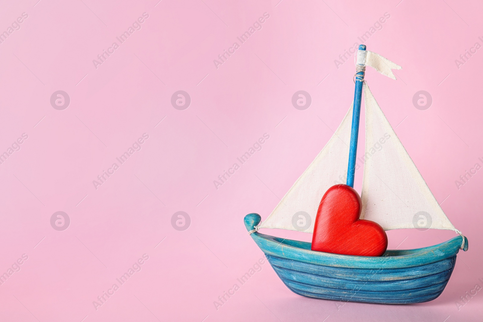 Photo of Toy boat with red heart on color background. Space for text