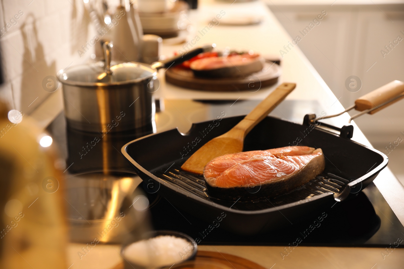 Photo of Frying pan with fresh salmon steak on cooktop
