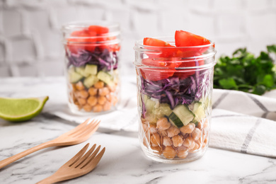 Photo of Healthy salad in glass jars on marble table