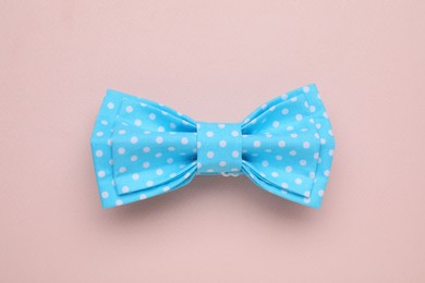 Stylish light blue bow tie with polka dot pattern on beige background, top view