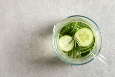 Photo of Jug of fresh cucumber water on grey table, top view. Space for text