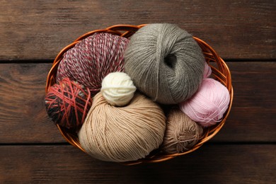 Photo of Soft woolen yarns on wooden table, top view
