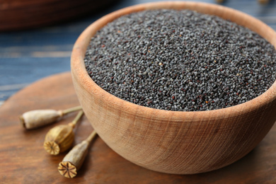 Photo of Poppy seeds in bowl on wooden board, closeup