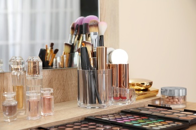 Photo of Set of luxury makeup products, accessories and perfumes on dressing table in room. Space for text