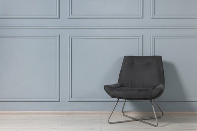 Photo of Comfortable armchair near grey wall in room, space for text