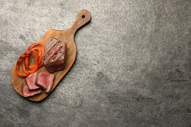 Photo of Delicious grilled beef steak with spices on gray table, top view. Space for text