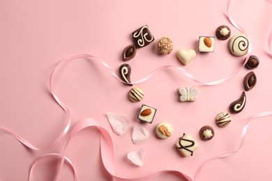 Photo of Heart made with delicious chocolate candies on light pink background, flat lay