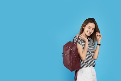 Photo of Happy woman with backpack on light blue background. Space for text