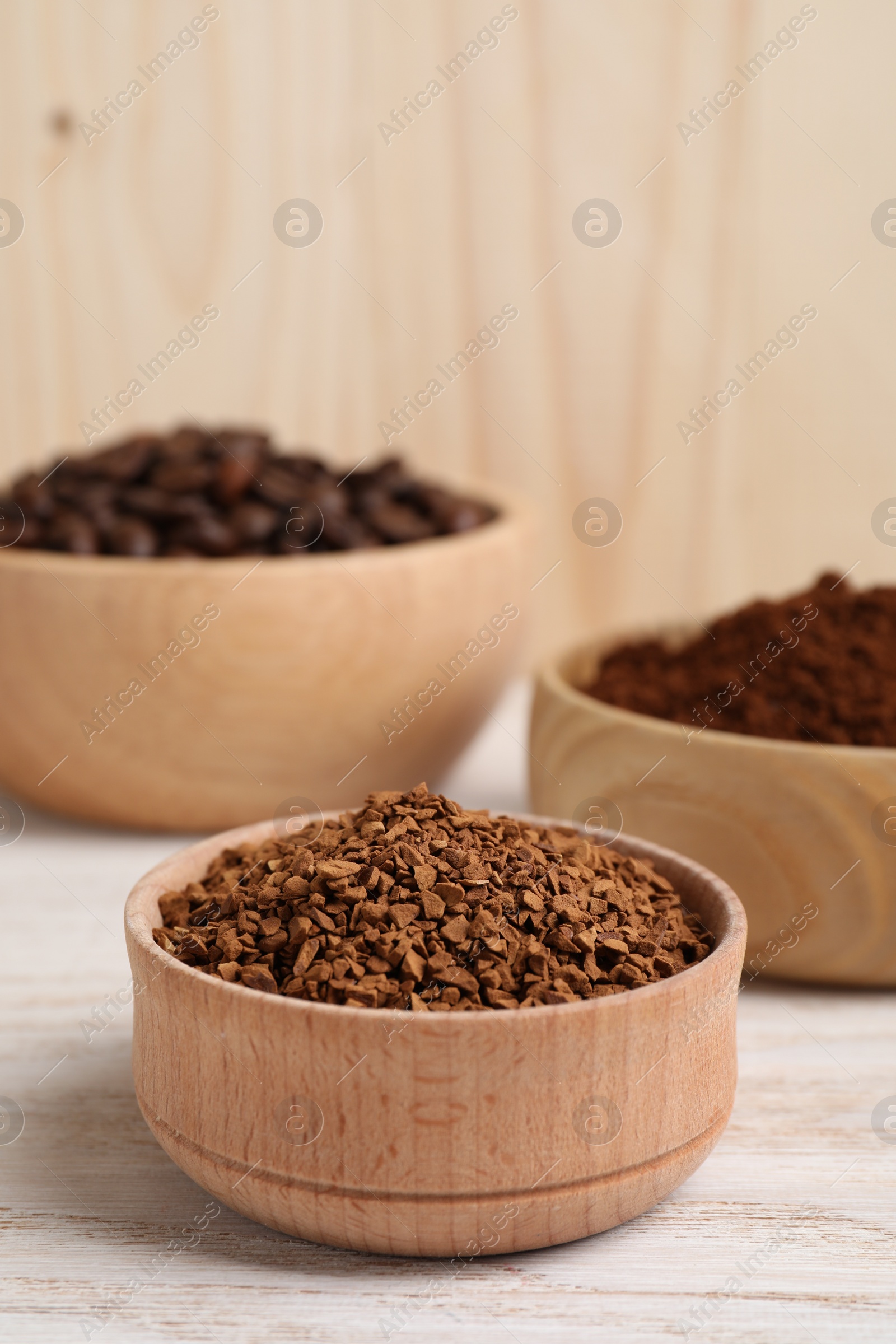 Photo of Bowls with different types of coffee on white wooden table