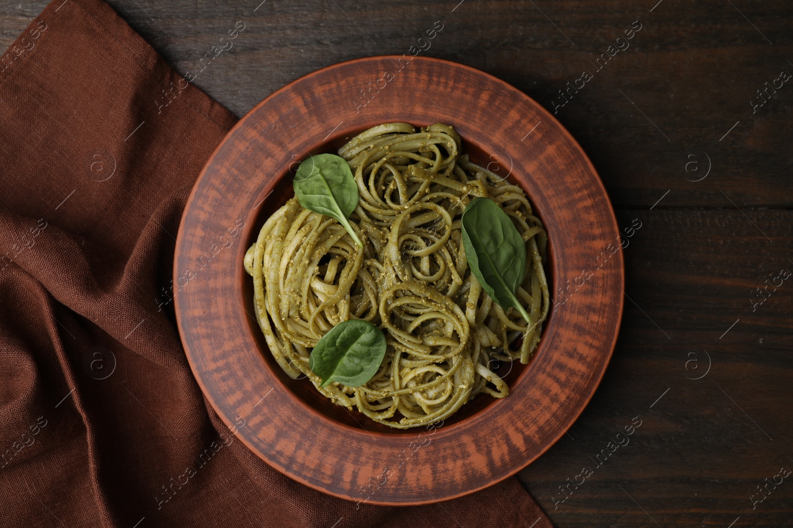 Photo of Tasty pasta with spinach on wooden table, top view