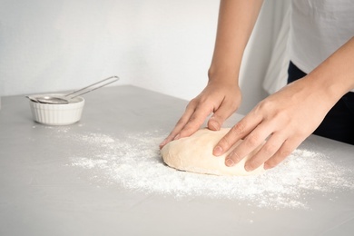 Woman making dough for pastry on table