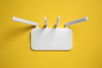 New white Wi-Fi router on yellow background, top view