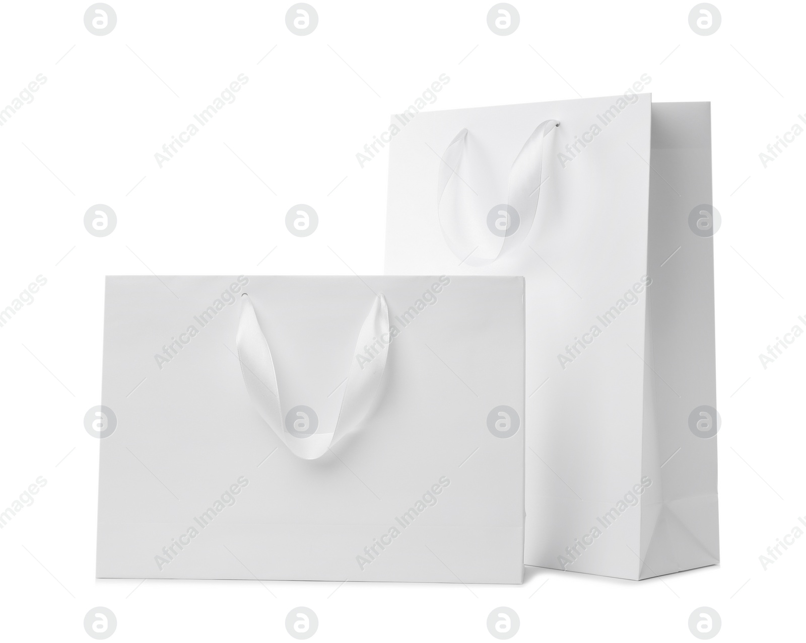 Photo of Paper shopping bags with ribbon handles on white background. Mockup for design