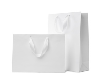 Photo of Paper shopping bags with ribbon handles on white background. Mockup for design