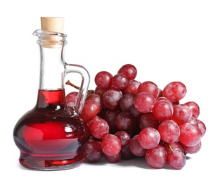 Glass jug with wine vinegar and fresh grapes on white background