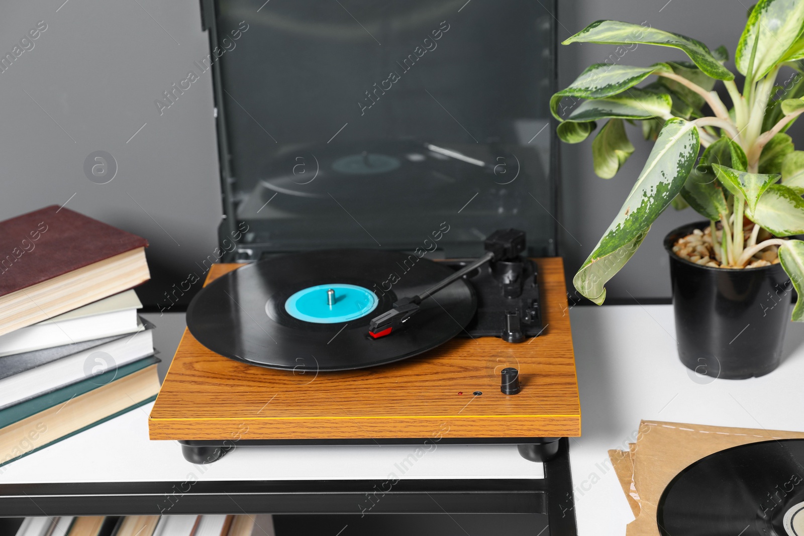 Photo of Stylish turntable with vinyl disc near grey wall in room