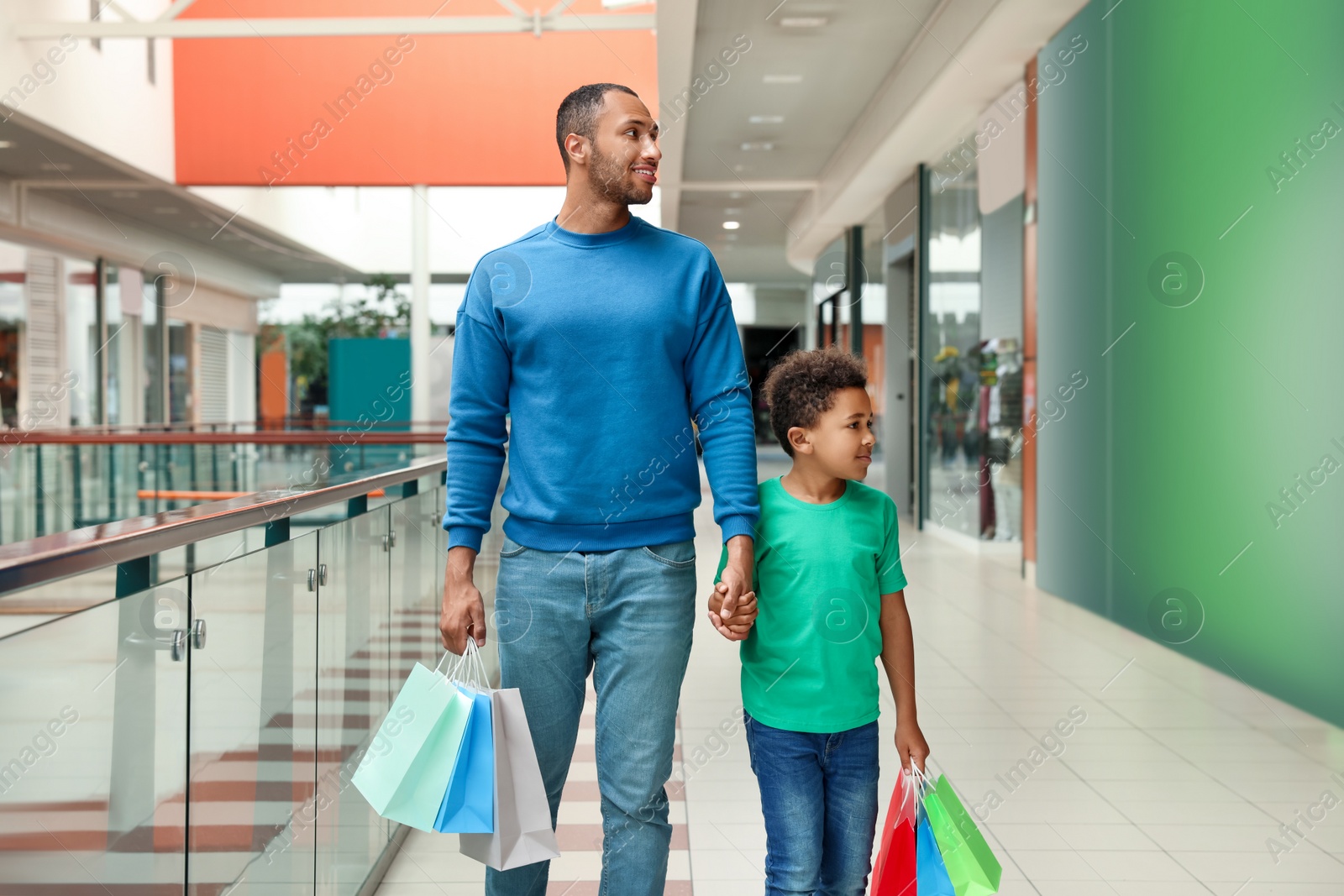 Photo of Family shopping. Happy father and son with colorful bags in mall