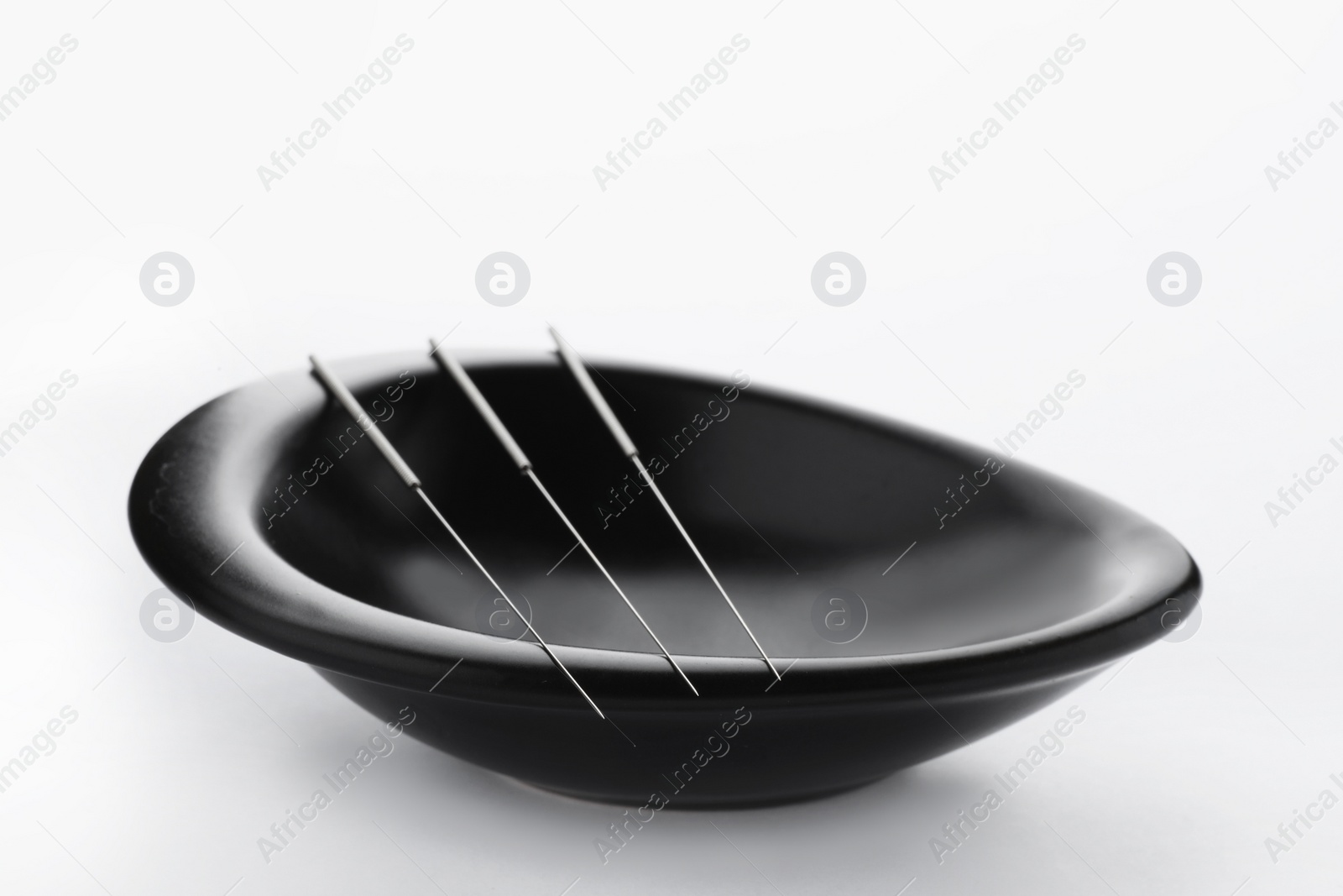 Photo of Bowl with needles for acupuncture on white background