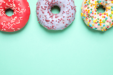 Delicious glazed donuts on turquoise background, flat lay. Space for text