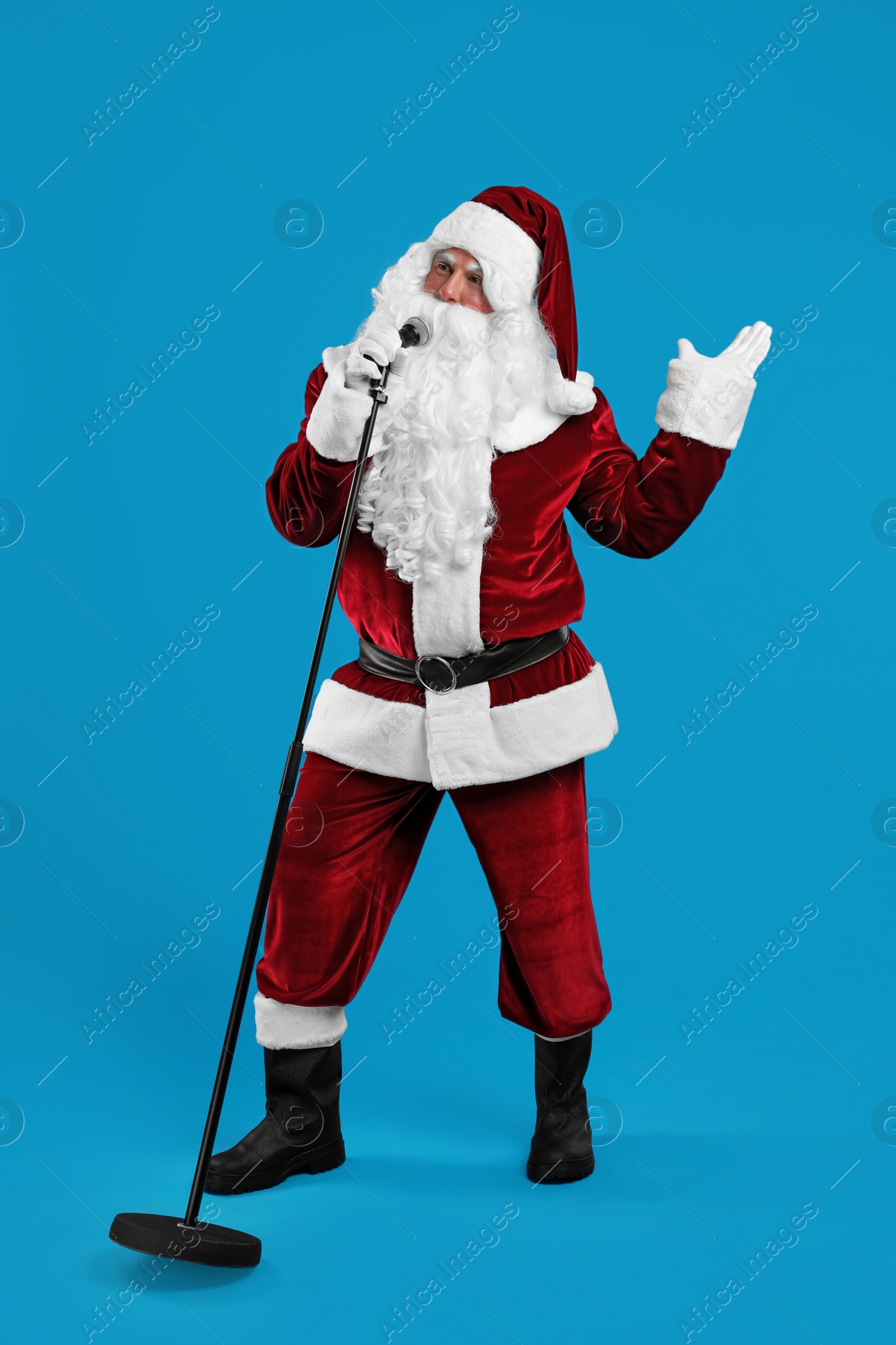 Photo of Santa Claus singing with microphone on blue background. Christmas music