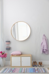 Stylish hallway interior with round mirror on white wall