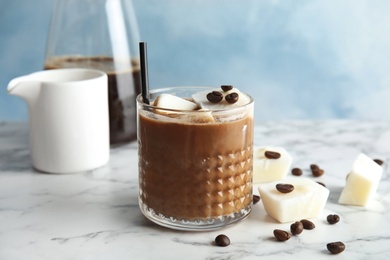 Composition with coffee drink and milk ice cubes on table against color background