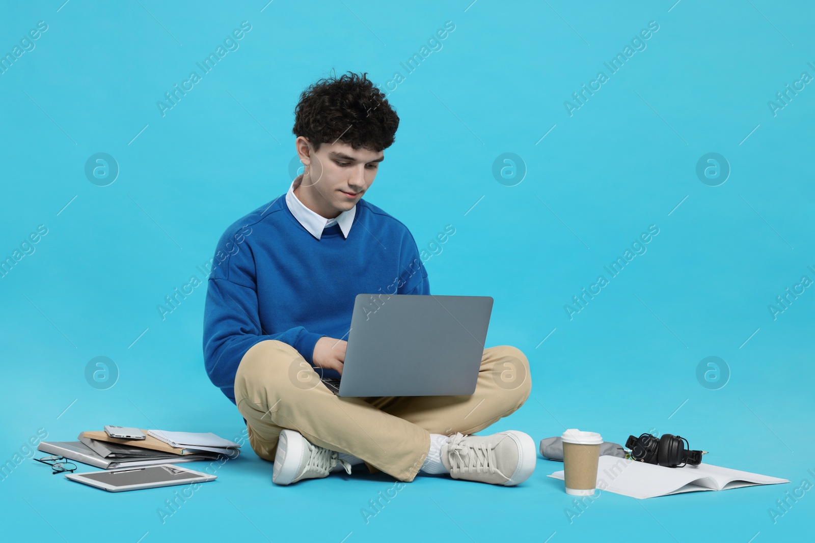 Photo of Portrait of student with laptop and stationery on light blue background