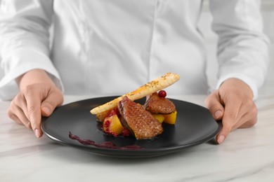Photo of Chef with delicious dish at marble table, closeup