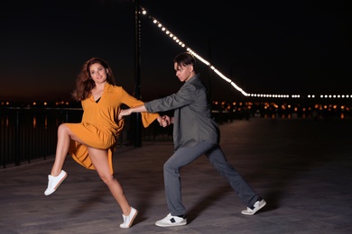 Photo of Beautiful young couple practicing dance moves in evening outdoors