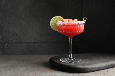 Photo of Cocktail glass of delicious fresh watermelon juice with lime on grey table. Space for text