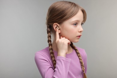 Little girl with hearing aid on grey background