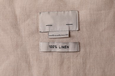 Photo of Clothing label on beautiful beige garment, top view