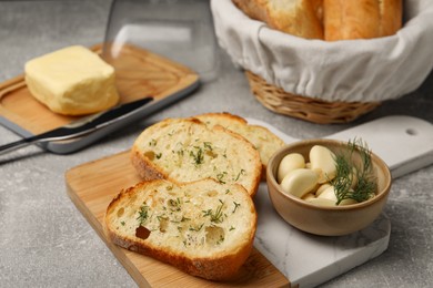 Photo of Tasty baguette with garlic and dill served on light grey table