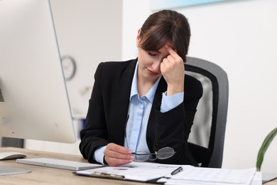 Overwhelmed woman with glasses at table in office