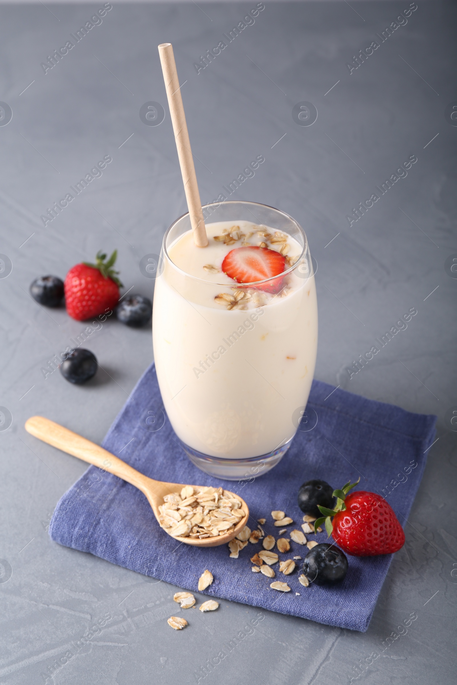 Photo of Tasty yogurt in glass, oats and berries on grey table