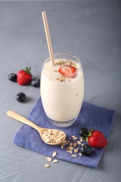 Tasty yogurt in glass, oats and berries on grey table