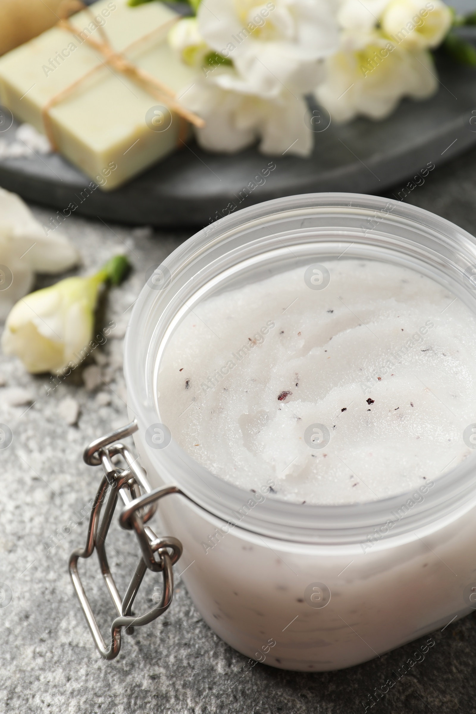 Photo of Body scrub in glass jar on grey table, closeup