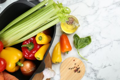 Photo of Black pot with round spatula and different products on white marble table, flat lay